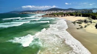 Nefes kesici ve çarpıcı kıyı manzarası, temiz mavi gökyüzünün altındaki el değmemiş dalgaları ve kumlu kıyıları gösteriyor.