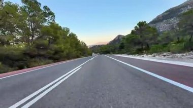Güneş batarken yemyeşil ve görkemli dağlarla çevrili güzel ve pitoresk bir yol.