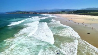 Bir hava sahili dalgalar ve güneşlenmelerle dolu muhteşem bir sahili yakalar ve sahildeki günlerinin tadını çıkarır.