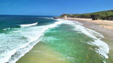 Sersemletici bir hava görüntüsü, berrak turkuaz su ve canlı yeşillik içeren pitoresk bir sahili gösteriyor..