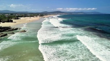 Sersemletici dalgalar durmaksızın sakin bir plaja çarpıyor ve yanında da doğal bir zemin var.