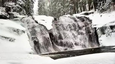 Nefes kesen bir kış şelalesi huzurlu ve karla kaplı bir doğada zarifçe akar.