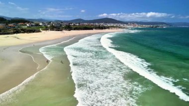 Nefes kesici bir sahil manzarası sergiler sakin dalgalar, altın kum uzantıları, ve yemyeşil yuvarlanan tepeler