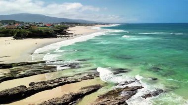 Canlı, gür yeşillik, dalgalı dalgalar ve sakin bir sahil şeridini barındıran nefes kesici sahil manzarası.