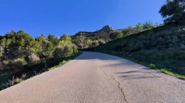 Berrak mavi bir gökyüzünün altındaki bereketli ağaçlarla çevrili dolambaçlı bir yolun nefes kesici güzel manzarası.