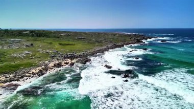 Hava manzarası, berrak turkuaz suları ve yemyeşil bitki örtüsüyle dramatik bir kıyı şeridi gösteriyor.