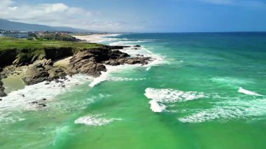 İnanılmaz güzel bir kıyı manzarası, berrak mavi gökyüzünün altında turkuvaz suları ve engebeli uçurumları sergiliyor.