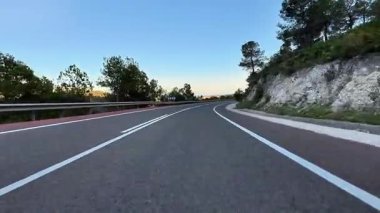 Gün batımında doğayla güzel bir şekilde çevrili dolambaçlı bir yolun nefes kesici ve resimsel manzarası.