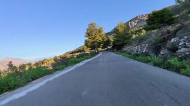 Güzel, dolambaçlı bir yol, zarif bir şekilde çevreleyen canlı yemyeşil ve şafak vakti nefes kesen dağlar.