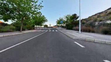 Bu pitoresk manzara boş bir şehir yolunu gözler önüne seriyor. Açık, mavi gökyüzünün altında uzun ağaçlarla dolu güzel bir yol.