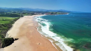 Çevresinde berrak turkuaz suları, dalgaları ve yemyeşil yemyeşil suları olan muhteşem bir sahil manzarası.