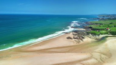 Çevresinde turkuaz suları ve yemyeşil tepeleri olan sakin bir plajın çarpıcı hava manzarasını tecrübe edin.