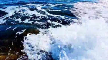 Çarpıcı görüntü kayalara çarpan okyanus dalgalarının engebeli arazide köpüklü desenler oluşturduğunu gösteriyor.