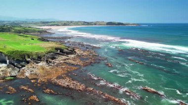 Sersemletici kayalık kıyı şeridinin nefes kesici manzarası berrak mavi gökyüzünün altındaki dingin turkuaz sularla birleşmiş.