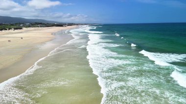 Göz kamaştırıcı ve pitoresk bir sahnenin sahnesinde yumuşak dalgalar, altın kum ve sakin, berrak gökyüzü sergilenir.