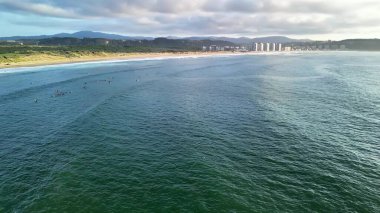 Nefes kesen hava manzaralı sörfçüler çarpıcı bir sahil şeridi boyunca güçlü dalgaları nazikçe sürüyorlar.