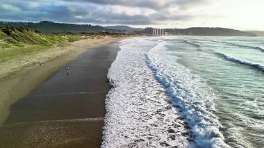 Muhteşem bir günbatımı manzarası sırasında kumlu bir sahilde usulca süzülen yumuşak dalgaların büyüleyici ve resimsel bir sahnesi.