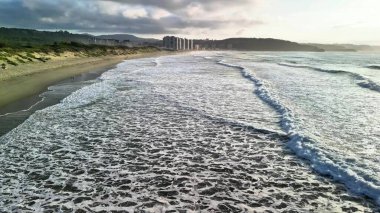 Gün batımında sakin bir plajda nefes kesici dalgaların tadını çıkar. Rahatlamak ve huzur bulmak için ideal.