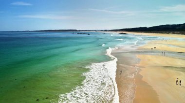 Canlı turkuaz suları ve güneşli altın kumlarıyla sakin bir sahili çeken nefes kesici bir hava çekimi..