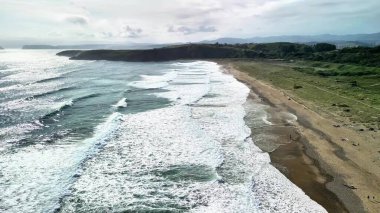 Sakin bir plaja çarpan okyanus dalgalarının çarpıcı görüntüsü, doğa ve rahatlama temaları için mükemmel..