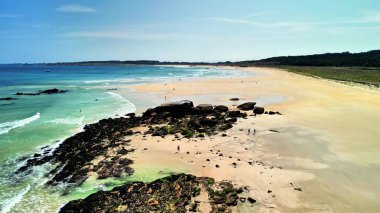 Altın kumları, berrak suları, yumuşak dalgaları ve güneşli bir gökyüzü olan sakin bir sahil.