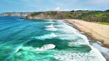 Hava manzarası, sakin dalgaları sergiliyor. Güzel kumlu bir kumsalla manzaralı bir zemin üzerinde buluşuyor..
