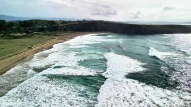 Güzel bir sahil şeridine çarpan dalgaların çarpıcı hava görüntüleri doğanın gücünü ve dinginliğini gözler önüne seriyor..