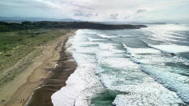 Nefes kesici bir hava manzarası çarpıcı dalgalar ve canlı kıyı manzaralarıyla nefes kesici sakin bir plajı gösteriyor.
