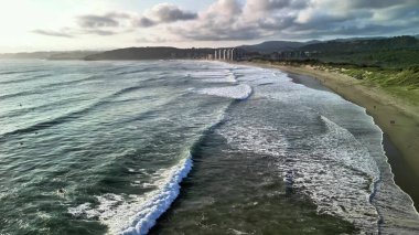 İnanılmaz güzellikteki gün batımında okyanus dalgalarının yavaşça kıyıya vuruşunu hissedin.