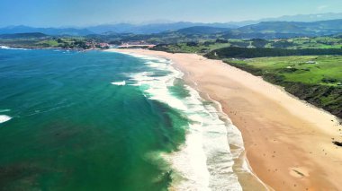 Hava görüntüleri görkemli dağlarla ve yemyeşil manzaralarla çevrili pitoresk bir sahili gösteriyor.