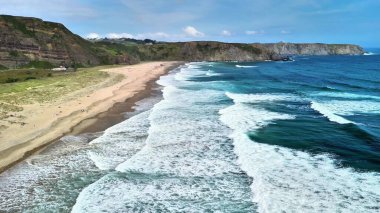Dalgaların sahile ve kayalıklara çarptığı çarpıcı bir sahil manzarasının nefes kesici güzelliğine dalmak.