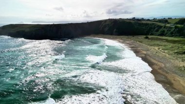 Nefes kesen bir hava manzarası çarpan dalgaları ve yemyeşil yeşillikleriyle çarpıcı bir kıyı şeridini ortaya çıkarıyor.