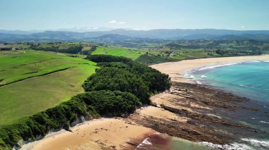 Nefes kesici bir hava manzarası, pırıl pırıl sularla kusursuz bir şekilde birleşen nefes kesici bir altın plaj sergiliyor.