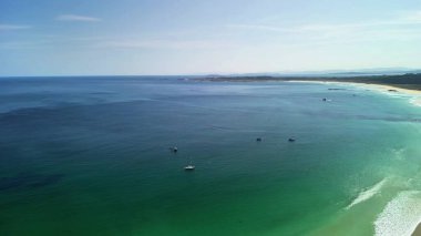 Nefes kesici bir hava manzarası berrak suları, yumuşak beyaz kumları ve yumuşak dalgaları olan sakin bir sahili gösteriyor.