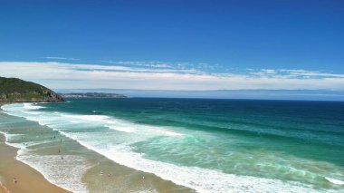 Dalgalar, yumuşak kum ve dalgalı gökyüzü ile nefes kesici bir sahil manzarası. Rahatlamak ve gevşemek için mükemmel.