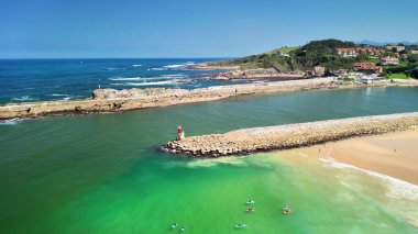 Resimli deniz feneri ve canlı yeşil suları olan muhteşem bir kıyı manzarası.