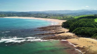 Bereketli yeşillik ve kristal berrak sularla çevrili sakin bir plajın nefes kesici hava manzarasını deneyimleyin.