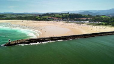 Bir sürü insanın olduğu güzel bir plajın havadan görünüşü, sersemletici bir manzarada bir iskele ve nazik dalgalar.