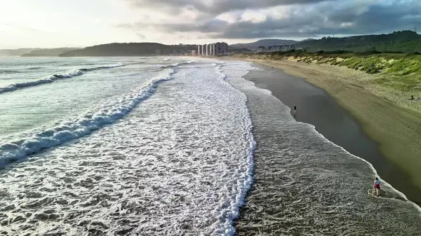 Sakin ve sakin bir sahil sahnesi yumuşak dalgaların sersemletici bir sahil zemininin altında yumuşak, sıcak kumları yaladığı.