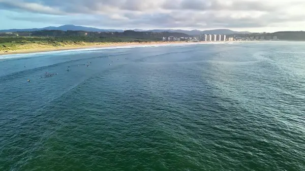 Nefes kesen hava manzaralı sörfçüler çarpıcı bir sahil şeridi boyunca güçlü dalgaları nazikçe sürüyorlar.