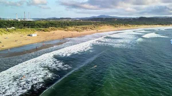 Güzel bir plajın çarpıcı hava görüntüleri dalgaları, kıyı şeridini ve güneşten zevk alan insanları yakalıyor..
