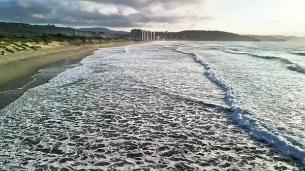 Gün batımında sakin bir plajda nefes kesici dalgaların tadını çıkar. Rahatlamak ve huzur bulmak için ideal.