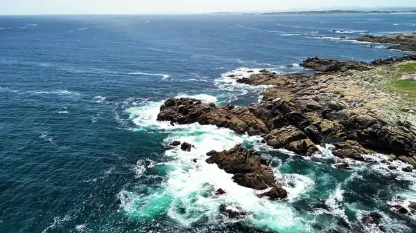 Nefes kesici hava manzaraları çarpıcı mavi okyanus dalgalarının çarptığı çarpıcı kayalık bir kıyı şeridini gösteriyor.