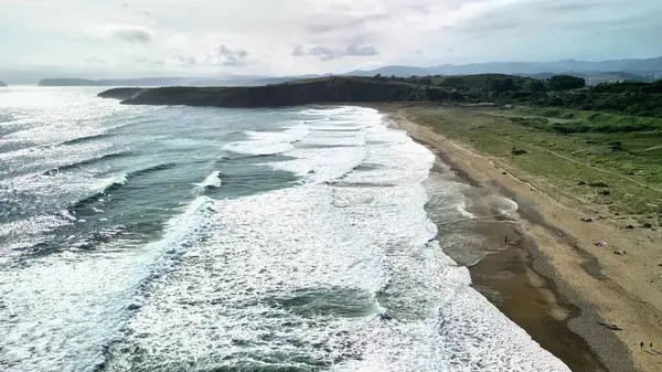 Sakin bir plaja çarpan okyanus dalgalarının çarpıcı görüntüsü, doğa ve rahatlama temaları için mükemmel..