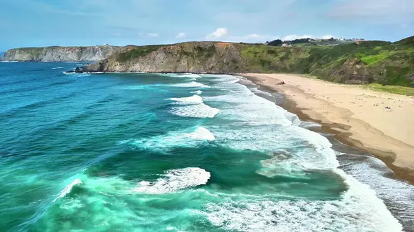 Hava manzarası, sakin dalgaları sergiliyor. Güzel kumlu bir kumsalla manzaralı bir zemin üzerinde buluşuyor..