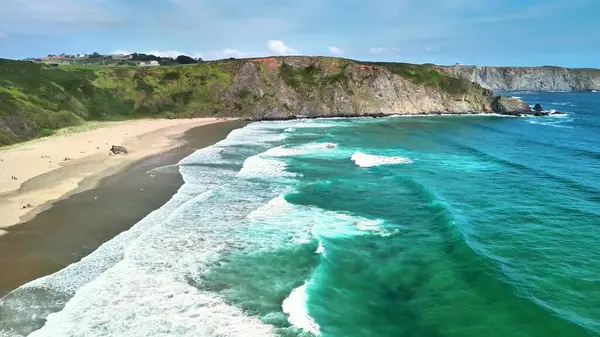 Turkuaz suları ve berrak gökyüzünün altındaki etkileyici uçurumlarla çarpıcı bir kıyı manzarası.