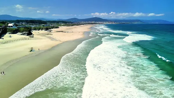 Kesinlikle nefes kesici bir kıyı manzarası kayan dalgaları, kumlu kıyıları ve açık mavi gökyüzünü aydınlatıyor.