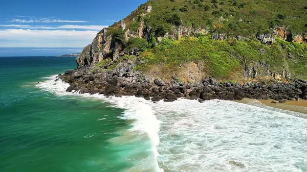 Bu çarpıcı sahil sahnesindeki nefes kesici uçurumları ve canlı okyanus dalgalarını keşfedin.