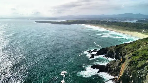 Görkemli uçurumlar ve canlı okyanus dalgalarıyla çarpıcı bir kıyı manzarasını gösteren hava görüntüleri.