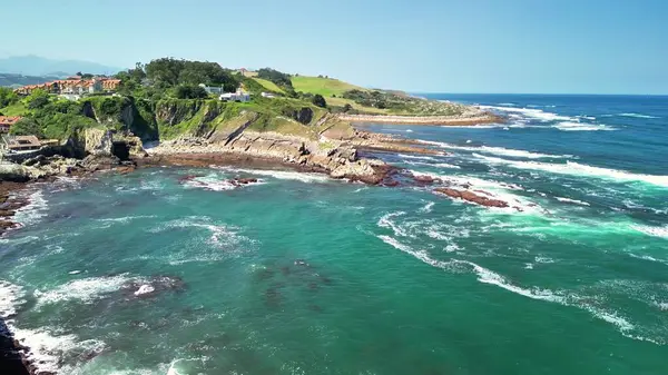 Nefes kesici bir hava manzarası, sakin mavi suları çevreleyen yemyeşil tepelerin yer aldığı pitoresk bir kıyı şeridi sergiliyor.